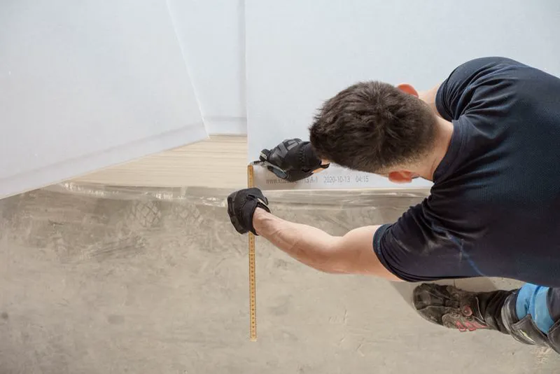 Installer measuring and cutting flooring panels during a renovation