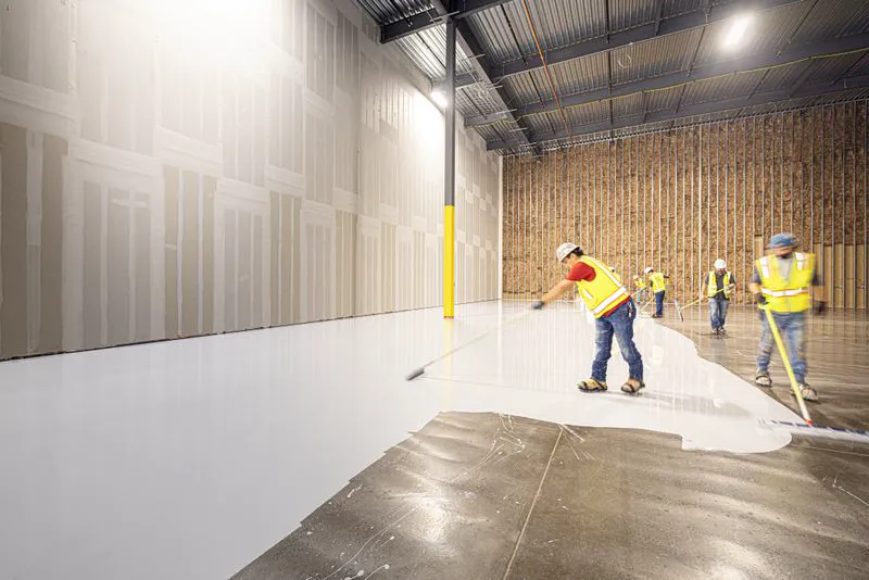 Crew working together to lay a fresh floor inside a building
